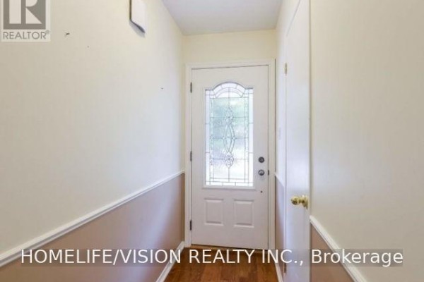 Interior entryway with beige walls, wainscoting, wood floor, and a glass-paneled front door. - 229 Village Wood Road, Oakville