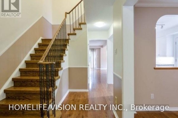 Foyer with wood flooring, a wooden staircase with metal railings, and a view of the hallway. - 229 Village Wood Road, Oakville