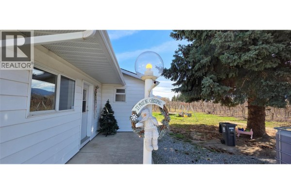 Exterior view of white siding with a Christmas tree and a vineyard. - 2292 Agar Road, Cawston