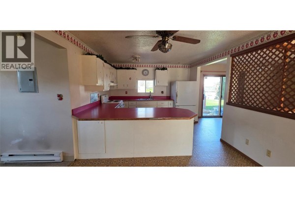 Kitchen with white cabinets, red countertops, and a ceiling fan. - 2292 Agar Road, Cawston