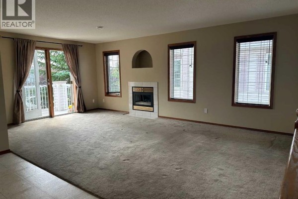 View of the dining area, fireplace, and staircase with wooden banister and carpeted steps. - 22d, 32 Daines Avenue, Red Deer