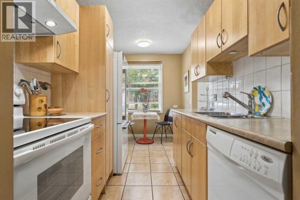 View of kitchen from stove showing sink, cabinets, and dining area. - 23, 330 Canterbury Drive Sw, Calgary