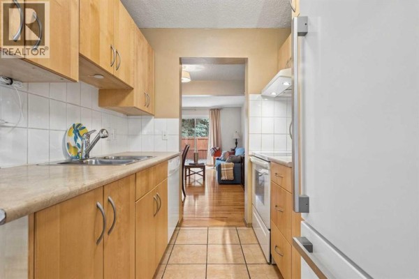 View from kitchen into living area showing hardwood floors and seating. - 23, 330 Canterbury Drive Sw, Calgary