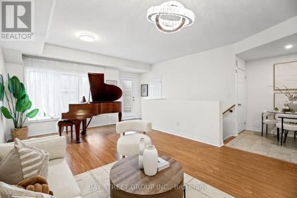 Living room with a grand piano, sofa, and a dining area with chairs visible. - 23 - 1 Eaton Park Lane E, Toronto