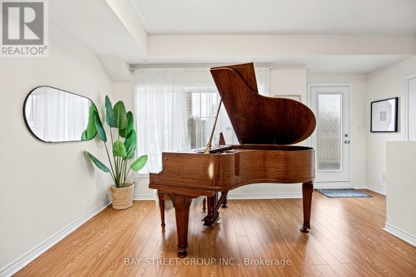 Close-up of a wooden grand piano in a bright living room with white walls and wood floors. - 23 - 1 Eaton Park Lane E, Toronto