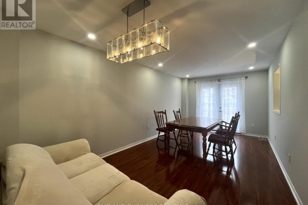 Living and dining area with a couch, wooden dining table, chairs, and hardwood floors. - 23 - 1588 South Parade Court, Mississauga
