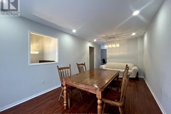 Dining area with a wooden table and chairs, looking towards a living room with a couch. - 23 - 1588 South Parade Court, Mississauga