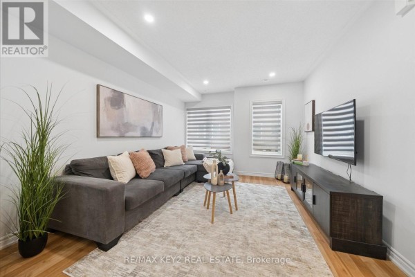 Living room with a large grey sectional sofa, patterned rug, and entertainment unit. - 23 - 2500 Hill Rise Court, Oshawa