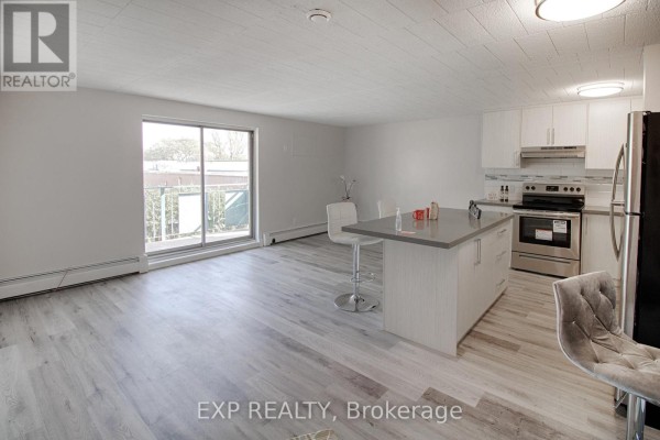 Open concept living area with a kitchen island, stainless steel appliances, and a sliding glass door. - 23 - 6287 O'neil Street, Niagara Falls