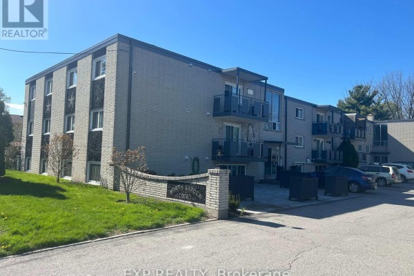 Exterior view of a light brick multi-family building with balconies and a paved driveway. - 23 - 6287 O'neil Street, Niagara Falls