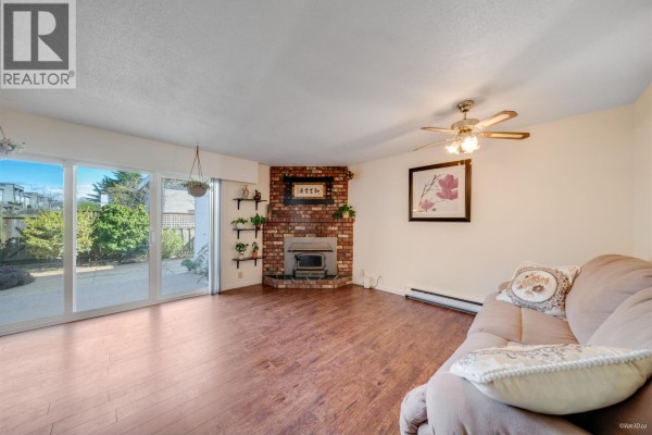 Living room with brick fireplace, hardwood floors, and sliding glass doors - 23 10840 Springmont Drive, Richmond