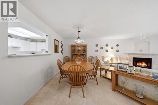 A dining area adjacent to a living room with a fireplace and a wooden dining set. - 23 12071 232b Street, Maple Ridge