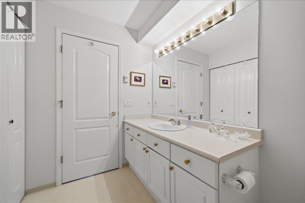 A bathroom vanity with a sink, large mirror with lights, and white cabinets. - 23 12071 232b Street, Maple Ridge
