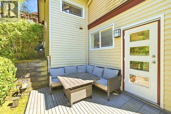 Outdoor patio area with sectional seating, a table, and a glass-paneled door. - 23 15 Forest Park Way, Port Moody