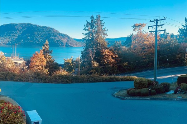 View of a calm bay with boats and forested hills under a clear blue sky. - 23 1700 Pritchard Rd, Cowichan Bay