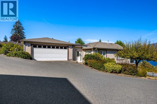 Exterior of a ranch-style home with beige siding and a white two-car garage door. - 23 1700 Pritchard Rd, Cowichan Bay
