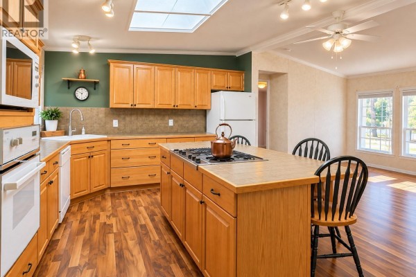 Living room with sofa, coffee table, and large windows overlooking trees. - 23 6820 Parklands Pl, Lantzville