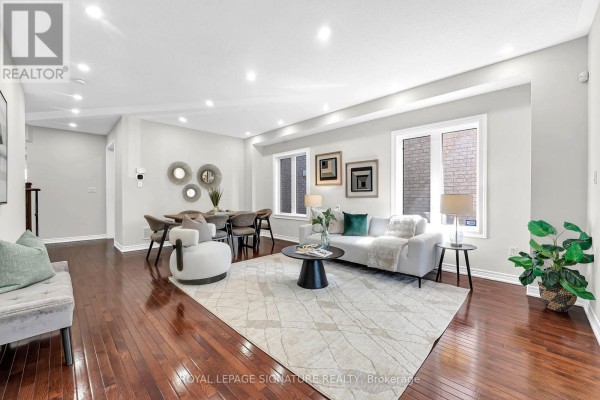 Living room and dining room with hardwood floors, fireplace, and modern furniture. - 23 Arrowpoint Drive, Brampton