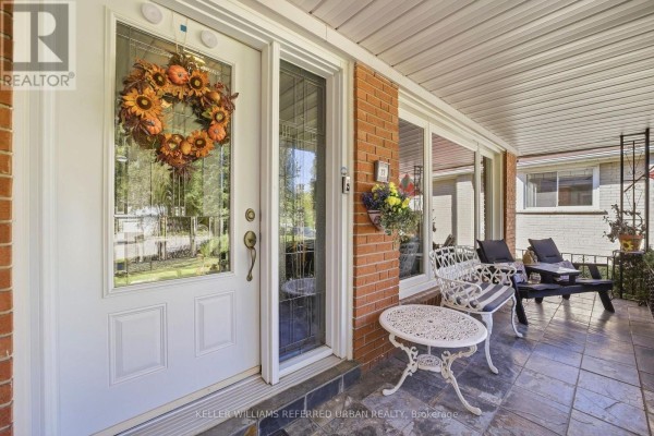 Covered porch entrance with a white door, sidelight, and seating. - 23 Banstock Drive, Toronto