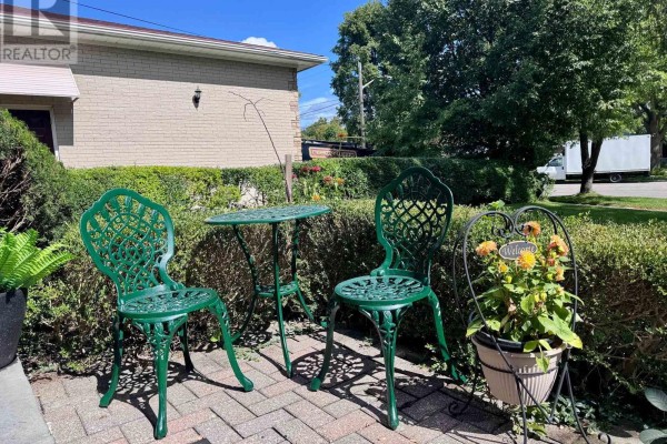 Green metal bistro set with a small table and two chairs on a paved patio. - 23 Banstock Drive, Toronto