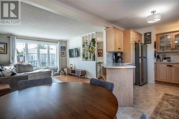 Open-concept living room, dining area, and kitchen with light wood cabinets. - 23 Barbour Drive, Mount Pearl