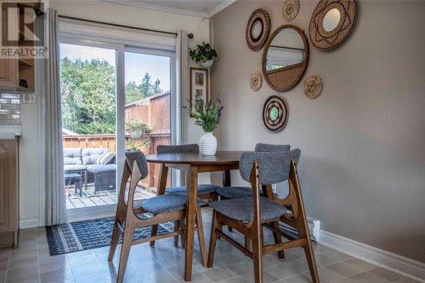 Dining area with a round wooden table, four chairs, and sliding glass doors to a deck. - 23 Barbour Drive, Mount Pearl
