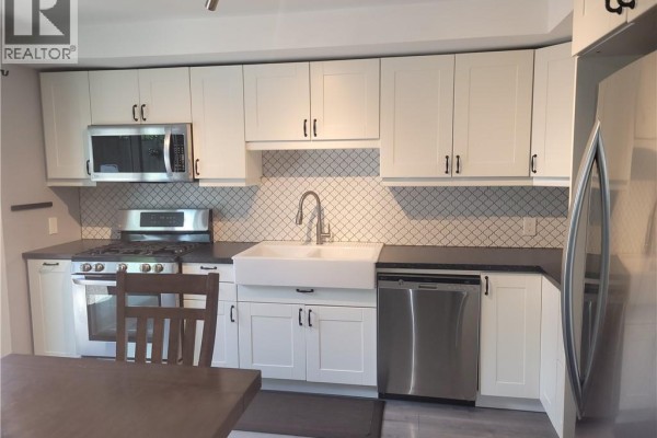 Kitchen with white cabinets, stainless steel appliances, gray backsplash, and a farmhouse sink. - 23 Bentley Place, Hamilton