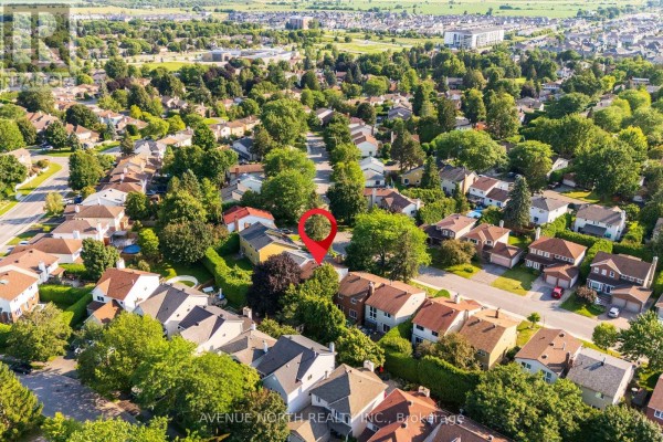 Elevated perspective of a residential area with homes, mature trees, and a pin indicating the property. - 23 Bluegrass Drive, Ottawa