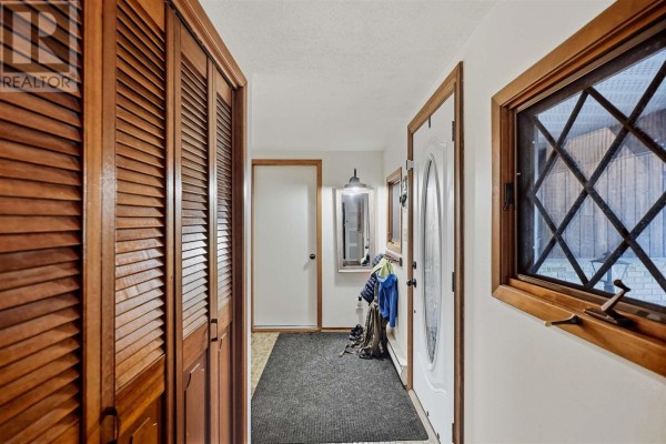Interior hallway with wood paneled walls, louvered closet doors, and a window with diamond panes. - 23 Country Club Pl, Sault Ste  Marie