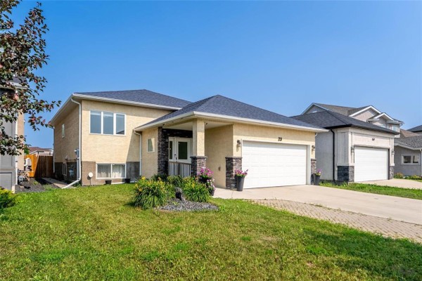 Side view of a beige, two-story house with a manicured lawn and stone accents. - 23 Driftwater Trail, Winnipeg