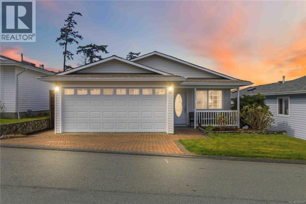 Exterior of mobile home with garage and porch at dusk with colorful sky. - 23 Eagle Lane, View Royal