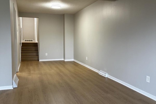 View of a living area with laminate flooring and a doorway leading to stairs. - 23 Fairlawn Crescent, Welland