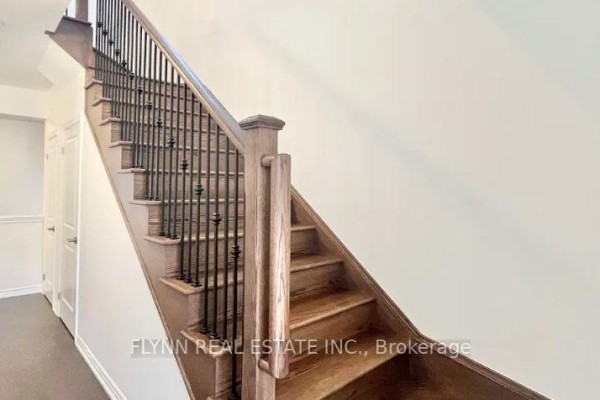 Wooden staircase with dark metal spindles and railing leading upstairs. - 23 Gemini Drive, Barrie