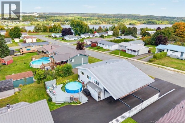 Aerial view of the bungalow and surrounding neighborhood with a body of water in the distance. - 23 Harding Drive, Nackawic