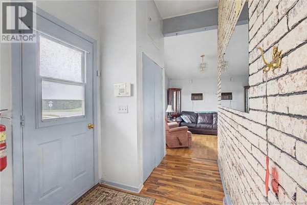 Interior view of an entryway with a light blue door, grey walls, wood floor, and hallway leading to living area. - 23 Harding Drive, Nackawic