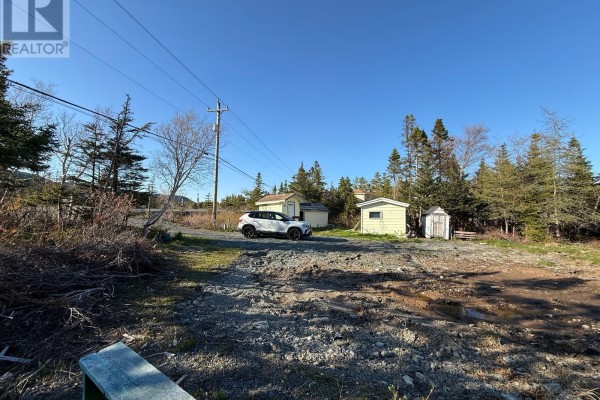 A white SUV parked by small utility buildings on a wooded lot with a blue shipping container. - 23 Hodgewater Line, South River