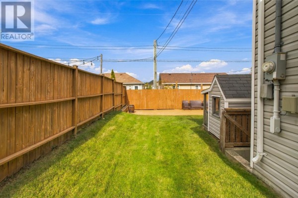 Backyard with green grass, a wooden fence, and a small shed. - 23 Hollyberry Drive, Paradise