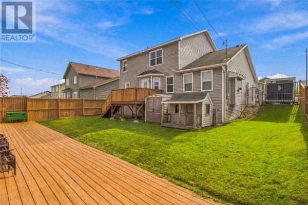 Backyard view showing a wooden deck, green grass, and a two-story house. - 23 Hollyberry Drive, Paradise