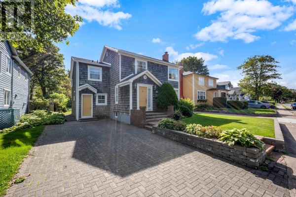 Side view of a two-story house with grey shingles and a grey brick driveway. - 23 Long Pond Road, St  John S