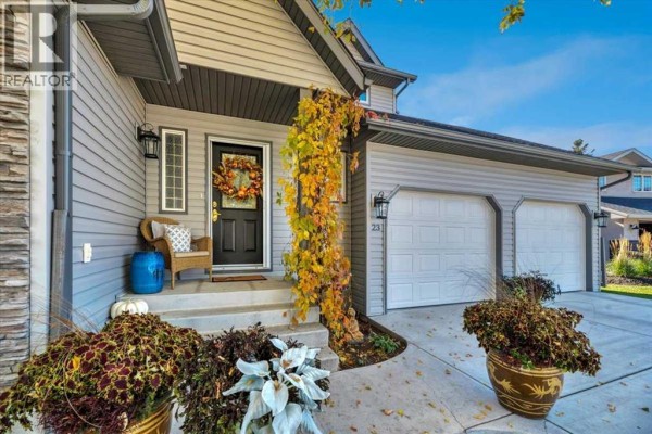 Close-up of the front entrance with a black door, wreath, chair, and a climbing vine. - 23 Madison Court, Strathmore