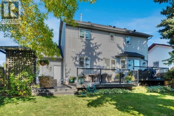 Rear view of the house showing a multi-level deck with patio furniture and a fenced backyard. - 23 Madison Court, Strathmore