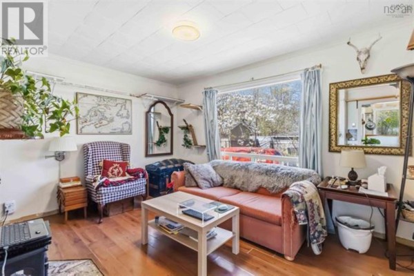 Living room with a salmon-colored sofa, armchair, coffee table, and large window. - 23 Military Road, Halifax