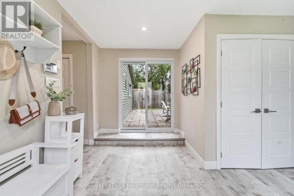 View of a carpeted staircase leading upstairs, with a view into a kitchen area with wooden cabinets. - 23 Park Road, Central Huron