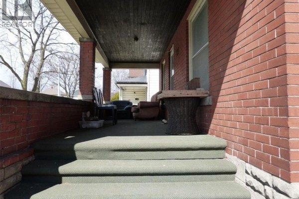 Covered porch with green carpeting, brick walls, and outdoor furniture. - 23 Queeens Avenue, Leamington