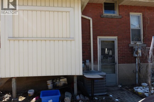 Side entrance of the house with a utility area and outdoor storage items. - 23 Queeens Avenue, Leamington