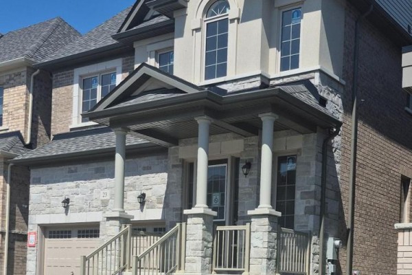 Detail of the covered front porch with stone pillars and a dark door. - 23 Rogerson Street, Clarington