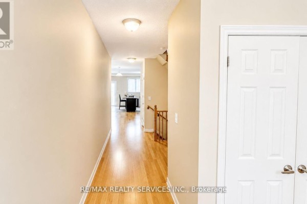 Interior hallway with light beige walls, a hardwood floor, and doors leading to other rooms. - 23 Sail Road, Brampton