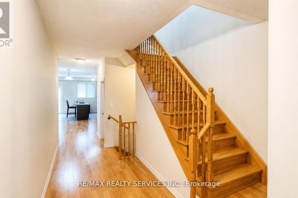 Interior hallway with a wooden staircase, hardwood floors, and doors leading to other rooms. - 23 Sail Road, Brampton
