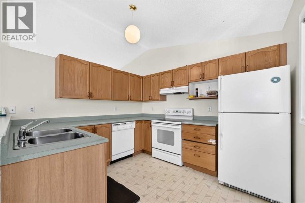 Kitchen with light wood cabinets, white appliances, and a pale green countertop. - 23 San Diego Manor Ne, Calgary