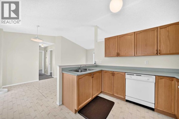 Corner view of a kitchen with light wood cabinets and white appliances. - 23 San Diego Manor Ne, Calgary